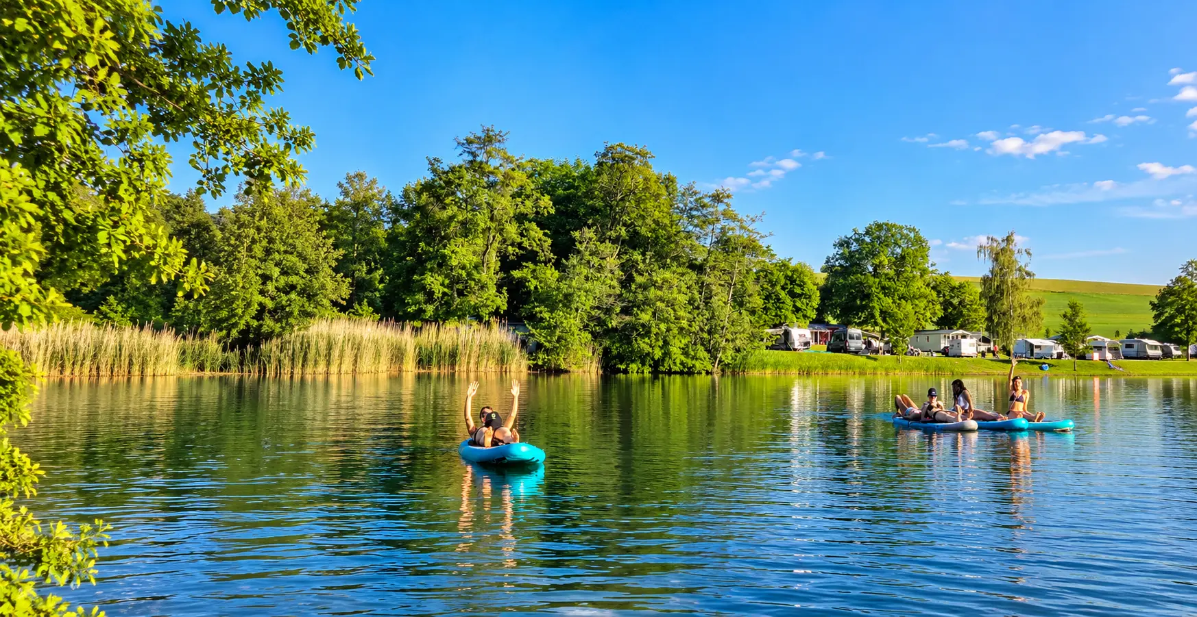Paddler auf dem Gederner See mit Schilfufer und Campingplatz im Hintergrund